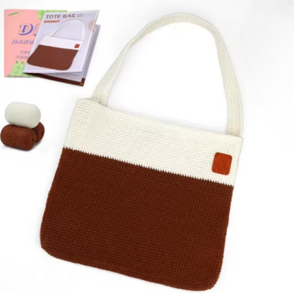 The Modern Crochet Tote Bag Kit includes two balls of cotton yarn, an instruction booklet, and materials to make a stylish two-tone tote with a cream upper section, brown lower section, and a small brown patch.