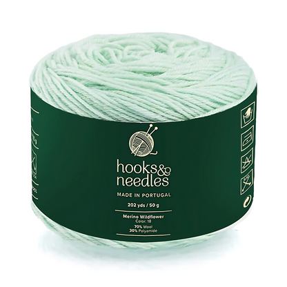 A 50g ball of Merino Wildflower Yarn—pale green, made in Portugal, 202 yards, and crafted with 70% Merino wool and 30% polyamide for warmth.