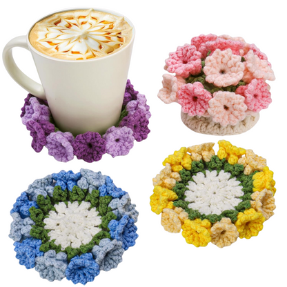 A white mug rests on a purple coaster from the Crochet Flower Coaster Kit 4pcs, with pink, blue, and yellow handmade floral coasters beside it—ideal for crochet flower lovers.