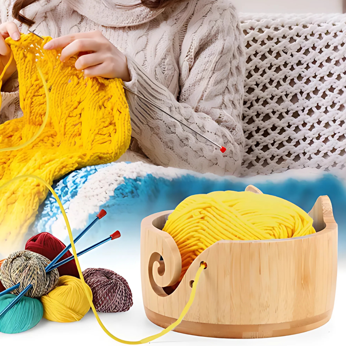 A person sits on a couch knitting with yellow yarn. A Cat Yarn Bowl holds more yellow yarn, and several colored yarn balls and knitting needles are nearby.