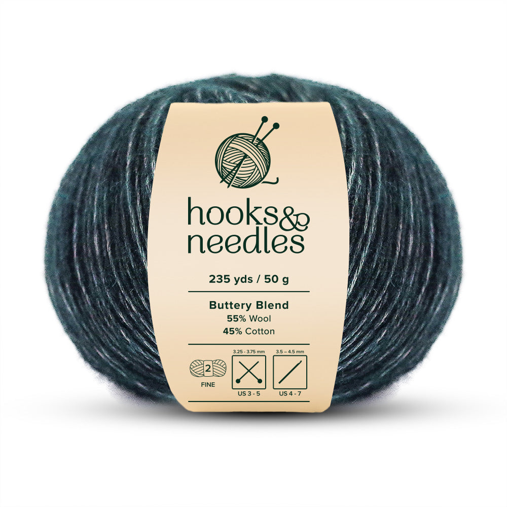 This Ball of teal yarn, known as "Buttery Blend Yarn 50g," features a luxurious mixture of 55% wool and 45% cotton. It is a fine-weight yarn offering 235 yards per 50g, and includes convenient needle size icons on the label.