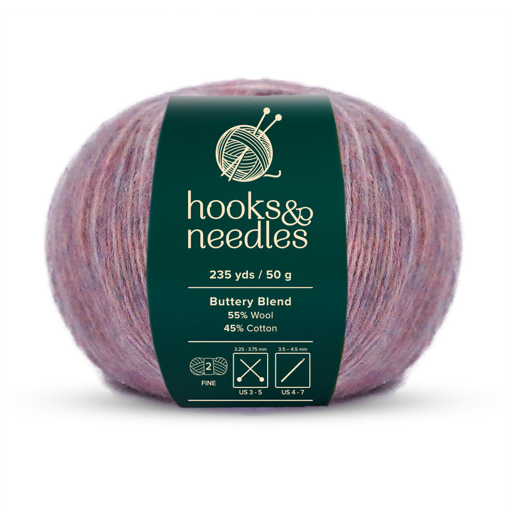 A ball of Buttery Blend Yarn 50g, labeled "hooks & needles," offers 235 yards of fine-weight yarn, crafted from a luxurious mix of 55% wool and 45% cotton.