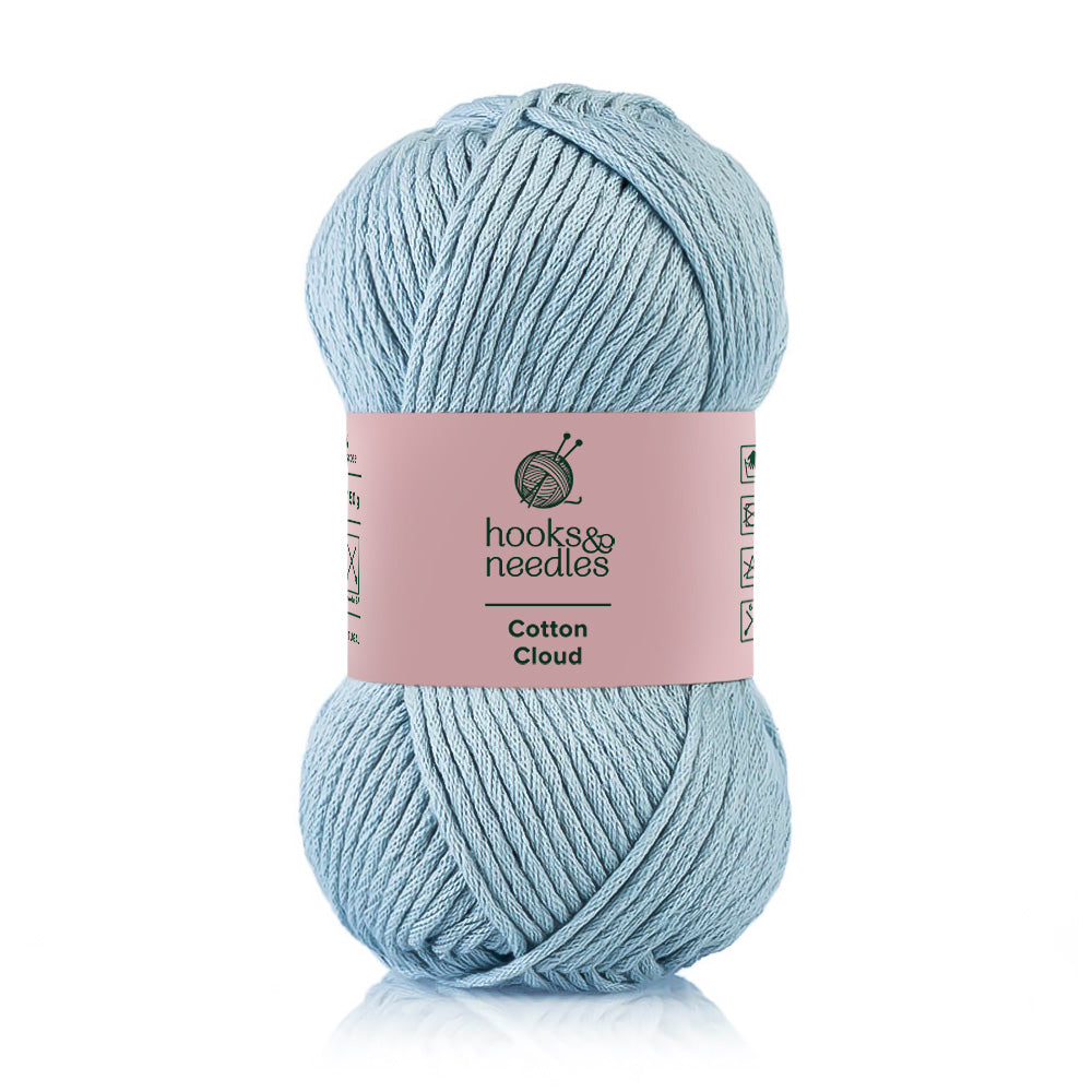 A skein of pastel blue 100% Cotton Cloud yarn labeled "Cotton Cloud" by hooks & needles, known for its hypoallergenic qualities.