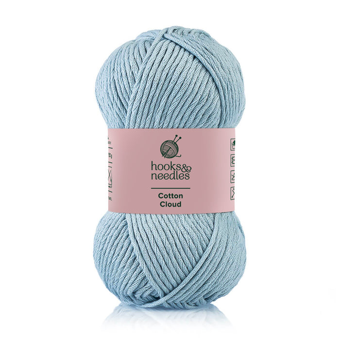 A skein of pastel blue 100% Cotton Cloud yarn labeled "Cotton Cloud" by hooks & needles, known for its hypoallergenic qualities.