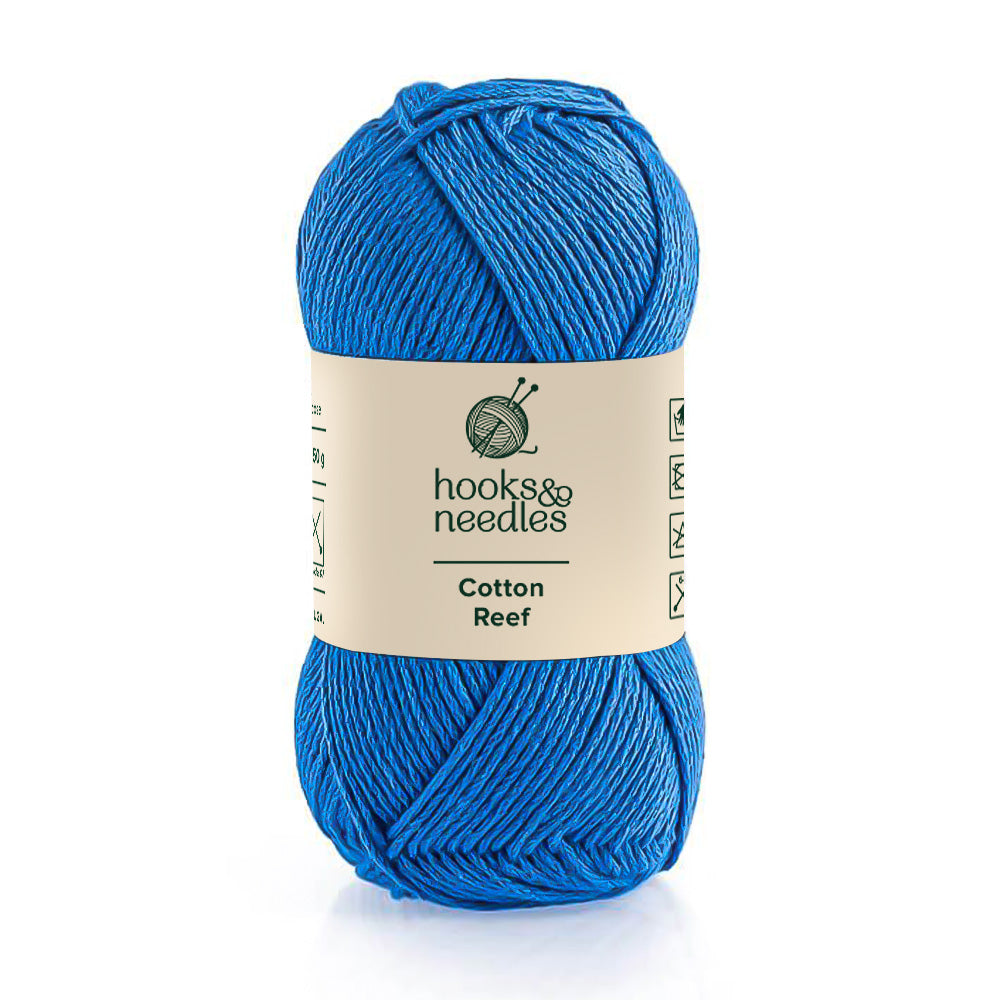 A skein of bright blue 100% Cotton Reef yarn from the brand "hooks & needles", known for its hypoallergenic qualities.