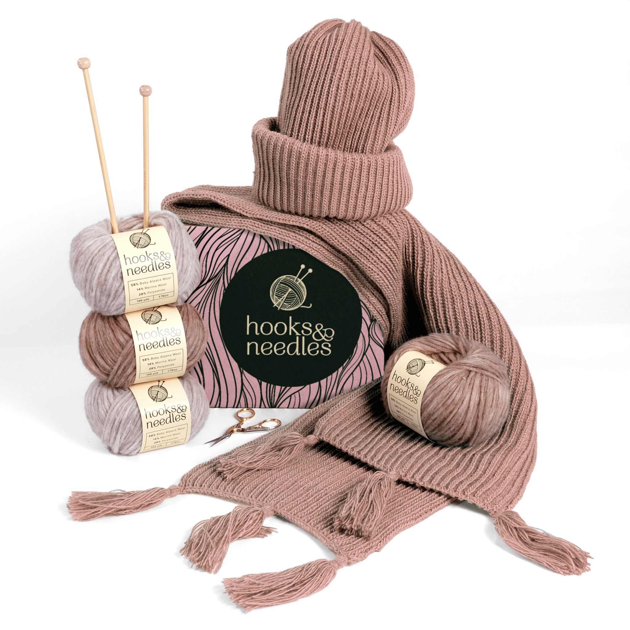 A display of [6-Month-Prepaid] Hooks & Needles Subscription Box #26 items including pink yarn, knitting needles, and a finished scarf and hat, neatly arranged on a white background.