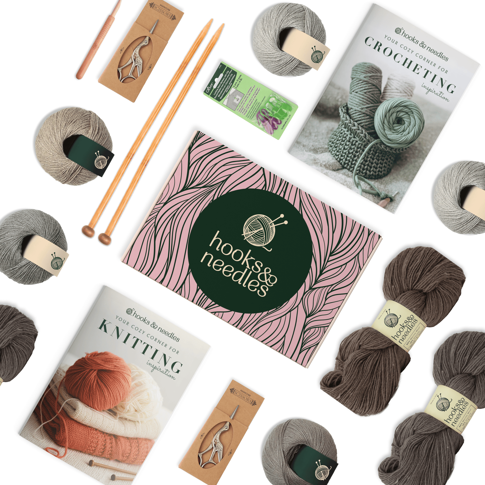 A flat lay of crochet and knitting supplies, including yarn balls, needles, and pattern books, arranged around a central green book titled "6-Month-Prepaid Hooks & Needles Subscription Box #23.