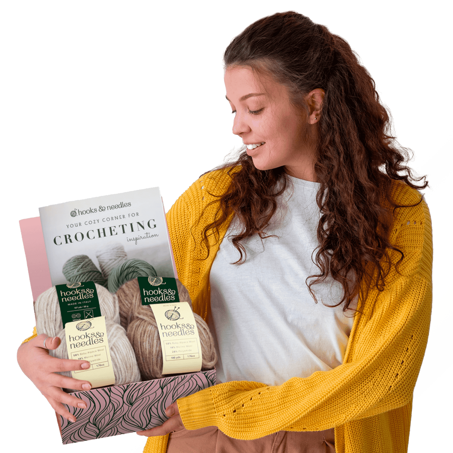 Woman in a yellow cardigan smiling at a [6-Month-Prepaid] Hooks & Needles Subscription Box #20 she is holding, with assorted yarn beside her, against a split background of white and light green.