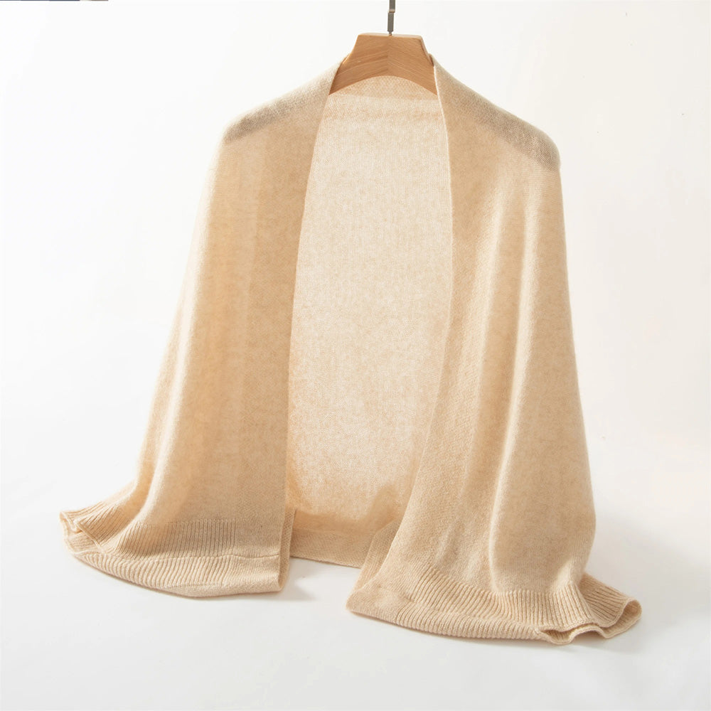 A luxurious Cashmere Knitted Poncho Scarf from the bundle collection is elegantly draped on a wooden hanger against a plain white background, exuding an aura of premium comfort and timeless style.