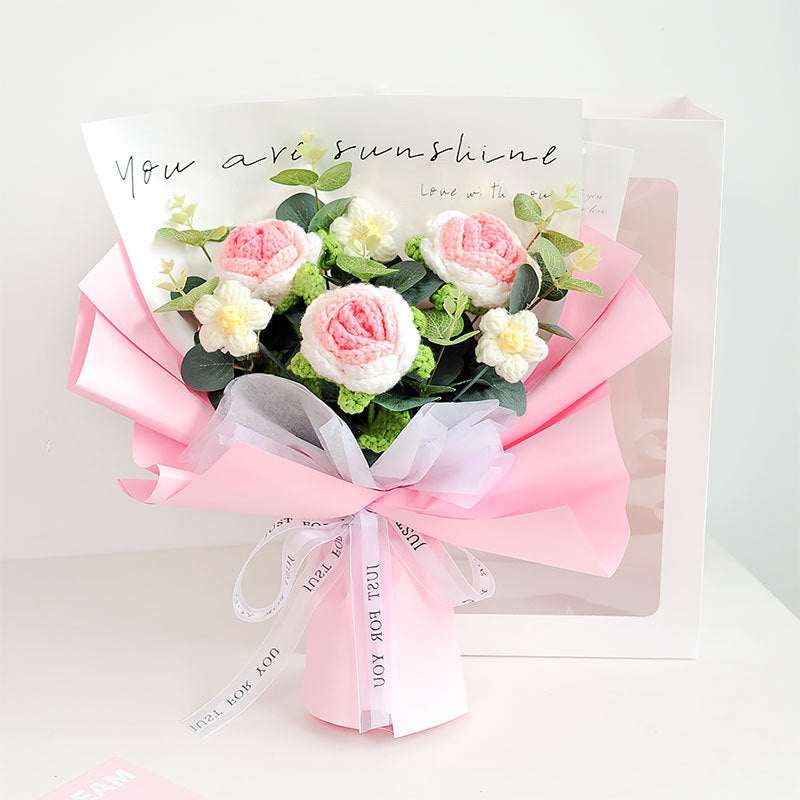 A bouquet of pink and white flowers, featuring handcrafted roses, wrapped in pink paper, accompanied by a card with the message "You are sunshine" has been replaced with the product name "Crochet Rose Bouquet - Timeless Blooms.