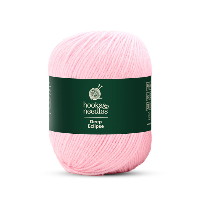 A light pink skein of Deep Eclipse Yarn 100g, featuring a dark green label that says "hooks & needles, Deep Eclipse." Made from 100% wool, this yarn is perfect for your crafting needs.