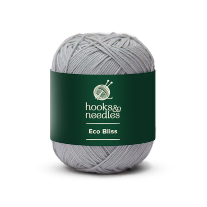 A ball of yarn labeled "Eco Bliss Yarn 50g" made from eco-friendly, organic cotton, featuring a gray color with a green band that displays a knitting logo.