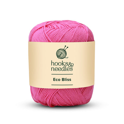 A ball of Eco Bliss Yarn 50g in pink, crafted from organic cotton, rests against a pristine white background.