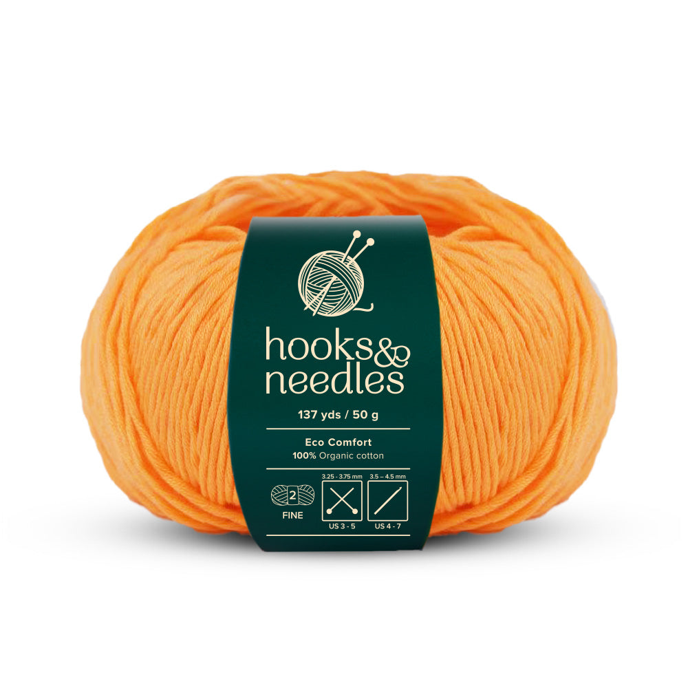 The Eco Comfort Yarn 50g, a ball of eco-friendly yarn labeled "Hooks & Needles," is crafted from 100% organic cotton, weighs 50 grams, and offers 137 yards for sustainable knitting projects.