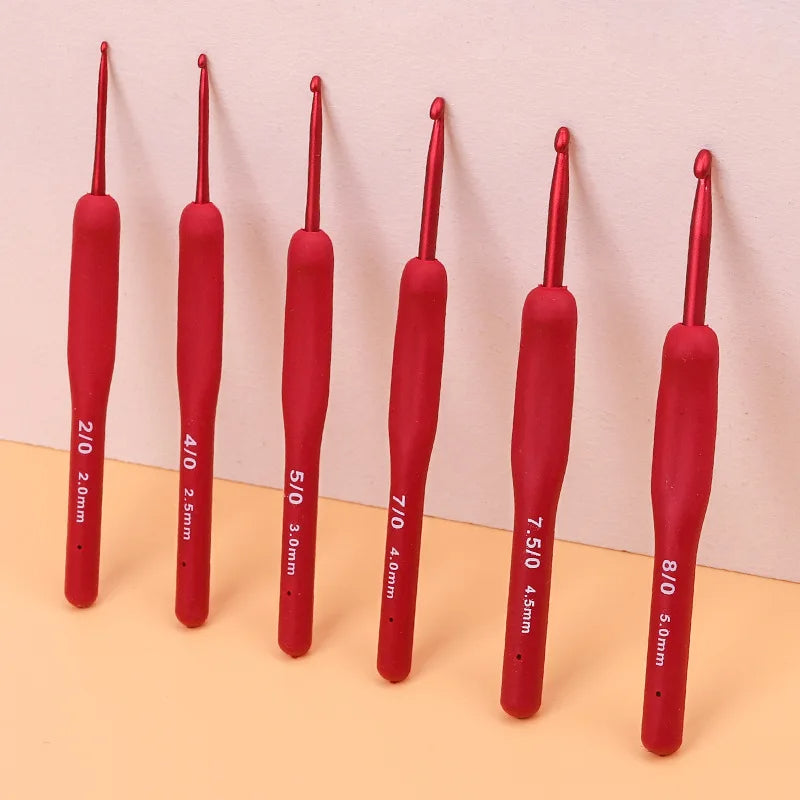 The colorful Ergonomic Crochet Hook Set 9 Pcs with Soft Grip Handles features six red ergonomic crochet hooks attractively displayed against a two-toned background, providing comfort and ease for your creative crocheting projects.