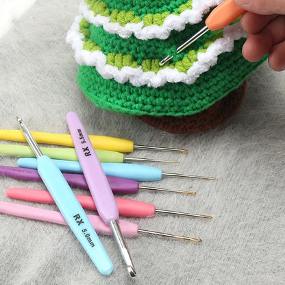 Colorful crochet hooks and a partially crocheted green and white item are shown. A hand is holding an ergonomic crochet hook from the Ergonomic Crochet Hook Set 16 Pcs with Case near the partially completed project.