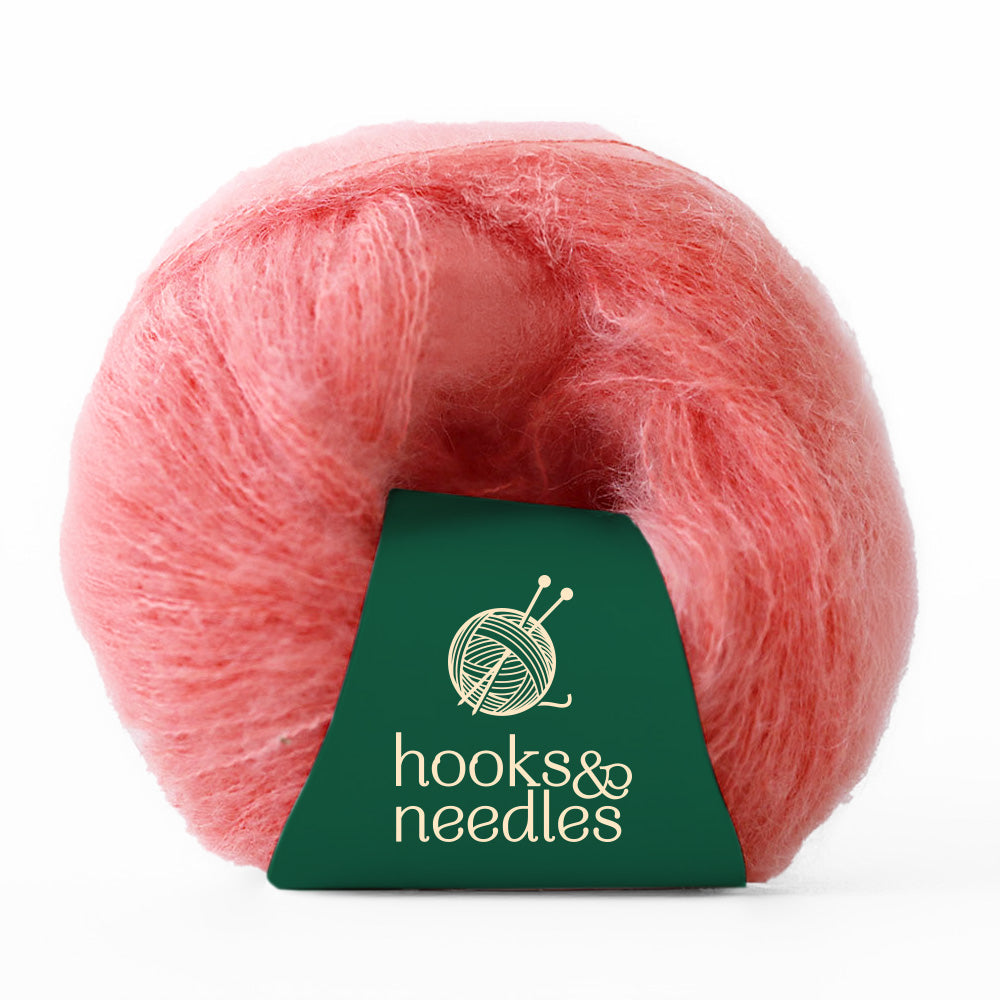 A delicate ball of Fusion Finesse Yarn 20g in a soft, fuzzy pink hue features a green label with the "hooks & needles" logo.