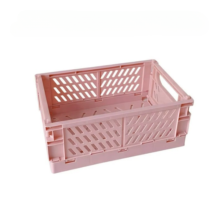 The Collapsible Storage Crate (10" x 7") for Knitting / Crocheting Supplies is a light pink crate with ventilation slats on the sides and handles on the ends, perfect for organizing your crocheting accessories or knitting supplies.