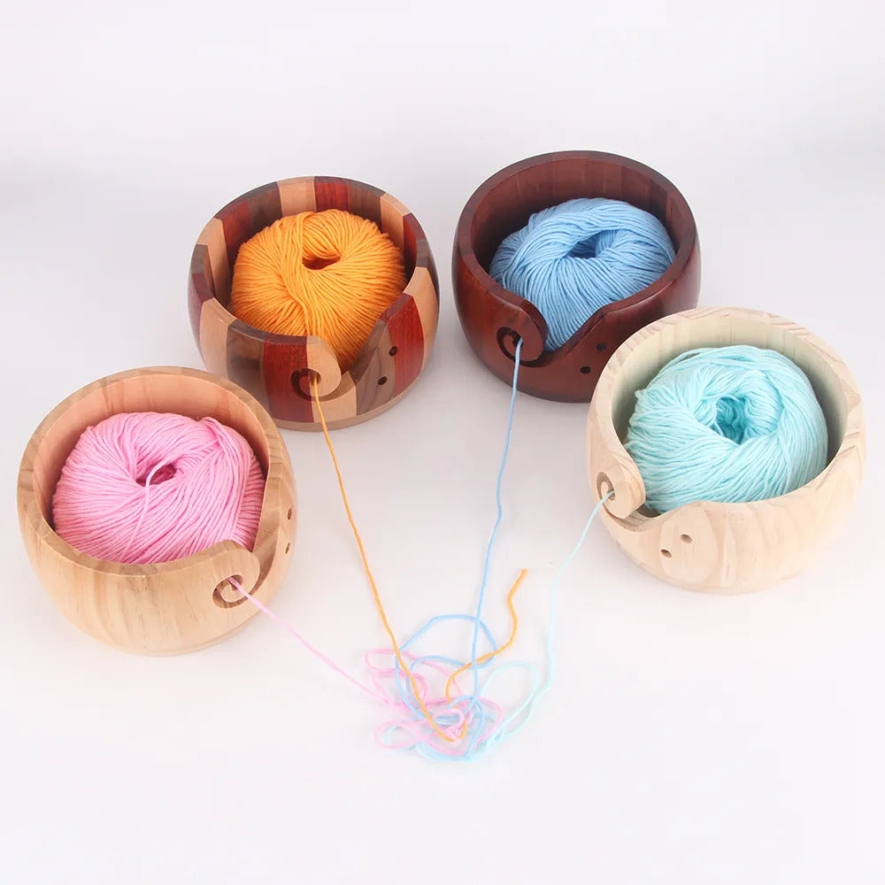 Handmade wooden yarn bowls with various colored yarns, three containing spools and one with loose yarn ends.