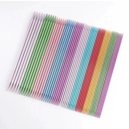 Rows of durable 55 Pcs Double Pointed Knitting Needle Set are neatly arranged on a white surface, showcasing a variety of colors and sizes in this premium knitting needle set.