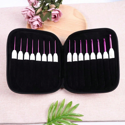 A black zippered case holding the Crochet Hook Set 16 Pcs with Case in purple and white is open on a table, surrounded by artificial flowers and a green leaf.