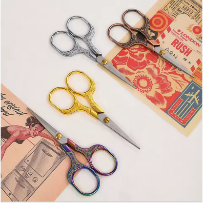 Three ornate pairs of Retro Stainless Steel Yarn Scissors in silver, gold, and multicolored are displayed on vintage floral paper—ideal for precise thread cutting or yarn trimming.