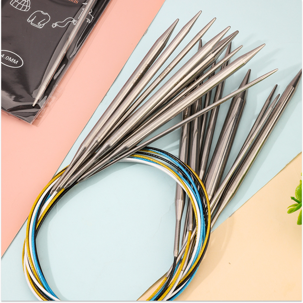 The Stainless Steel Knitting Needle Set, featuring interchangeable stainless steel tips and vibrant cables, is arranged on a pastel background—ideal for diverse knitting projects.