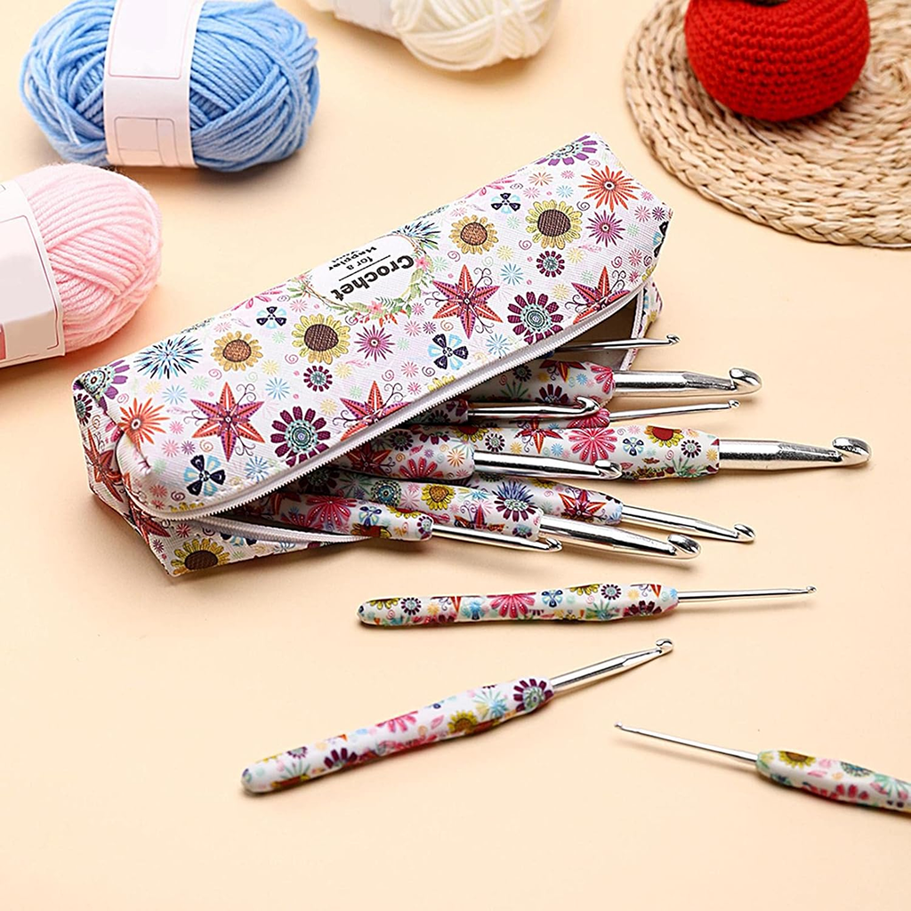 The 29-Piece Crocheting Kit: Perfect for Beginners features a floral-patterned case with seven colorful ergonomic hooks, surrounded by yarn balls and a red crochet item on a woven mat—ideal for beginner crocheters.
