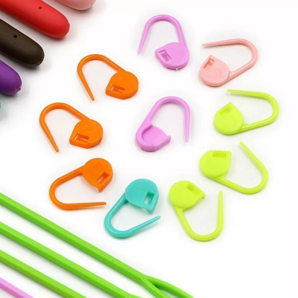 The Crochet Hook Set 31 Pcs with Bag - Beginner Friendly features assorted colorful stitch markers and green yarn needles, perfect for crafting, all neatly arranged on a white surface.