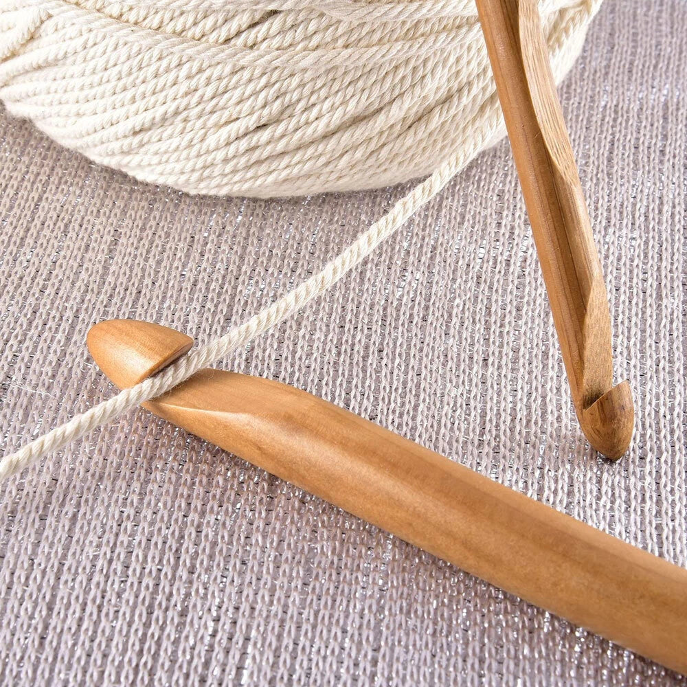 Close-up of Bamboo Crochet Hooks 12 Pcs and a ball of cream-colored yarn on a silver textured surface—an ideal set for sustainable crafting enthusiasts.