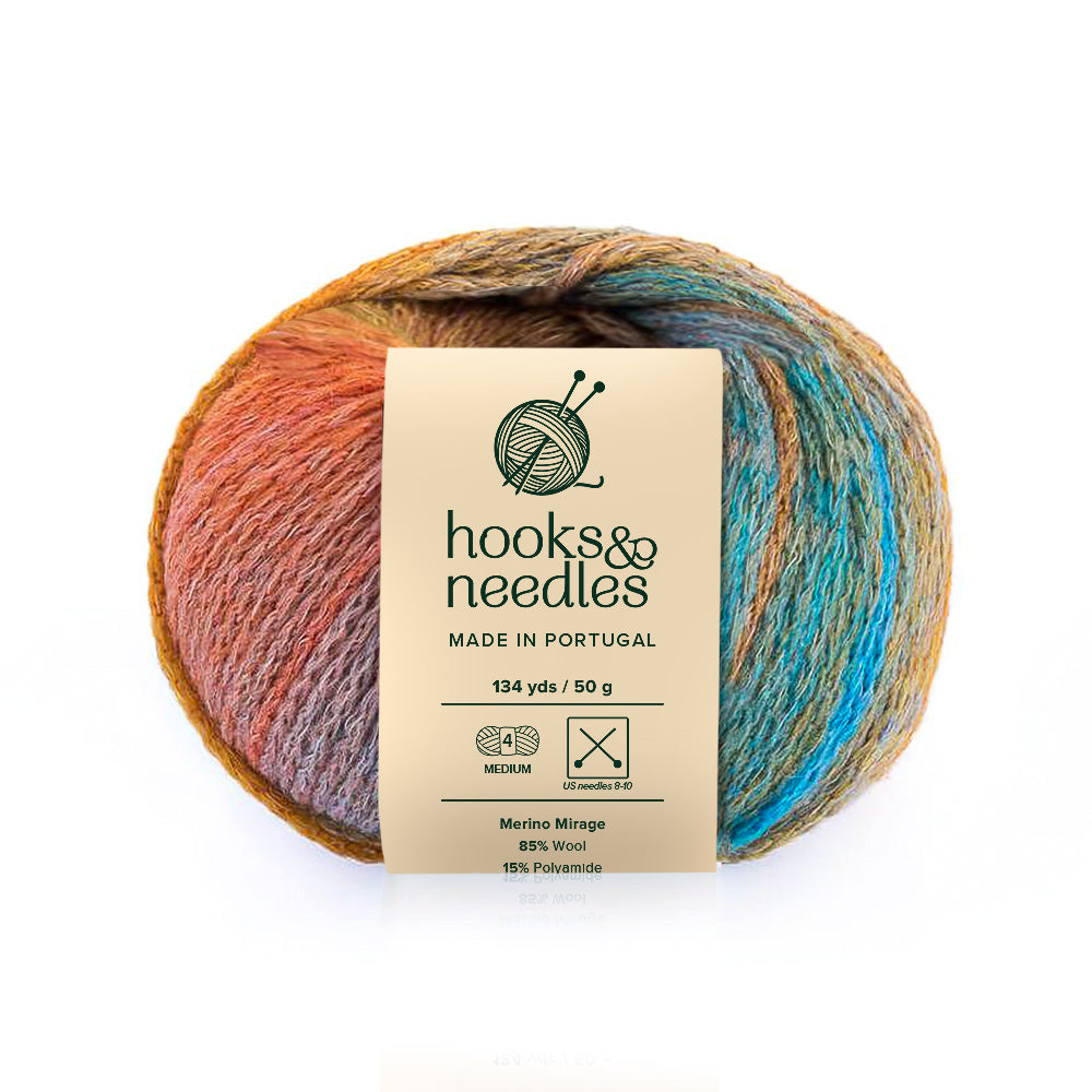 A multicolored skein of Merino Mirage yarn with a label from "hooks & needles" indicating it is made in Portugal, consists of merino wool and polyamide, and provides the yard