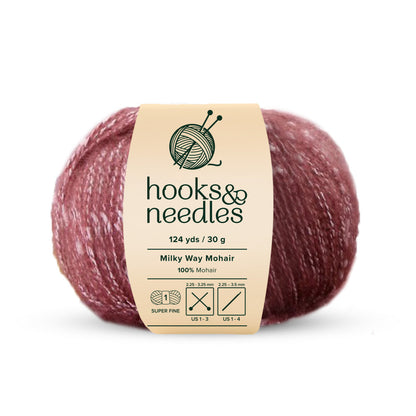 A 30g ball of "Milky Way Mohair Yarn," a super fine-weight and 100% mohair yarn, in a deep pink color, labeled "hooks & needles," with 124 yards.