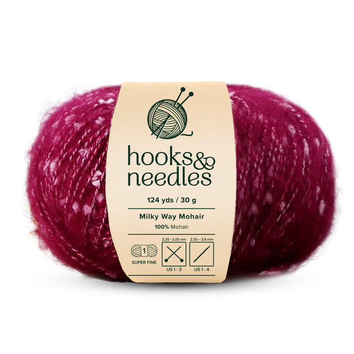 A ball of "Milky Way Mohair Yarn 30g" by Hooks & Needles, made from 100% mohair in deep red with white specks. The label provides information about its super fine-weight yarn nature, length, material, and recommended needle sizes.