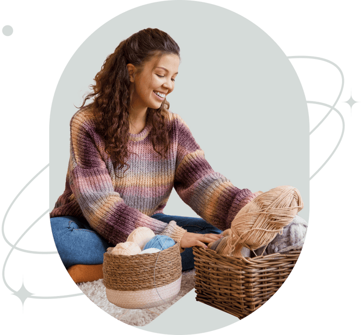 Woman with a basket of yarn smiling as she prepares to knit.