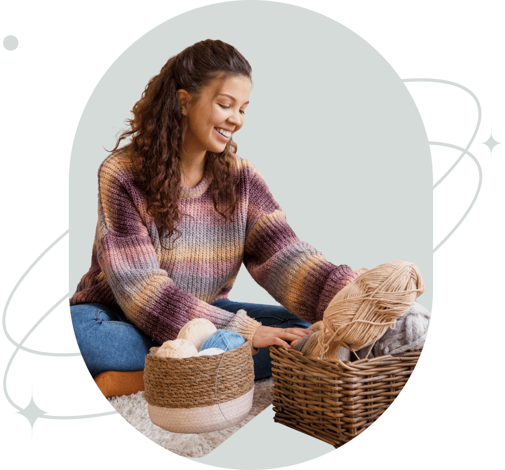 Woman with a basket of yarn smiling as she prepares to knit.