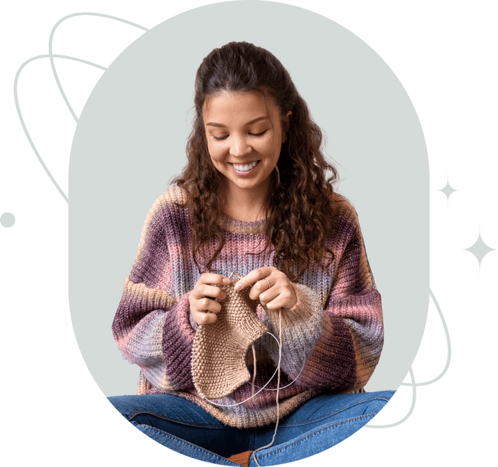 A smiling woman knitting with needles and yarn.