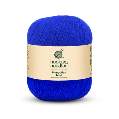 A skein of bright blue yarn, crafted with anti-pilling fiber and labeled "Mongolian Mist Yarn 50g," is wrapped in a beige band.