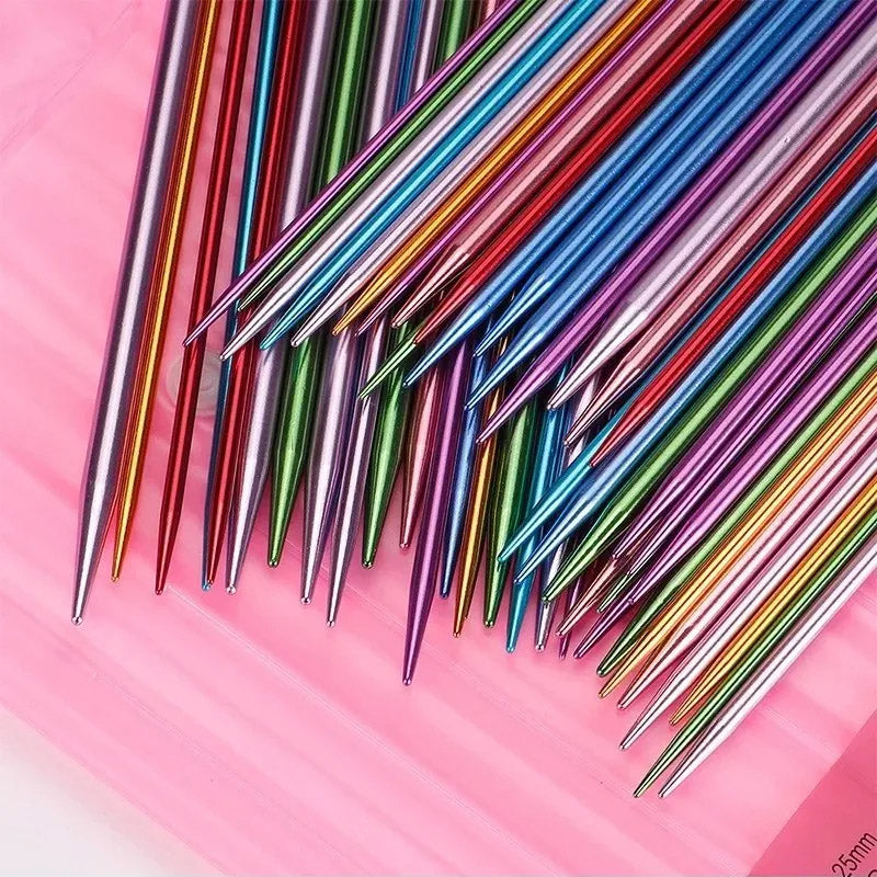 A collection of colorful, durable aluminum needles is artfully arranged in a fanned-out pattern on a pink background.