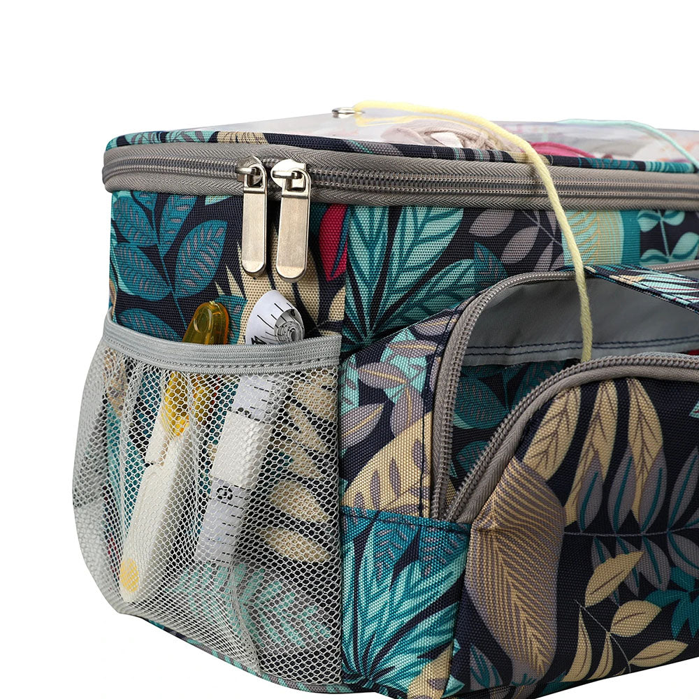 A patterned fabric Knitting Bag: Yarn Organizer with multiple compartments and silver zippers, perfect as a crafting organizer. It features a mesh pocket holding small items such as a thermometer and pens. The design includes teal, yellow, and gray leaves, making it an ideal knitting bag or yarn storage solution.