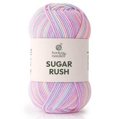 A skein of Sugar Rush Variegated Yarn by hooks & needles, super-fine weight and pastel-colored in soft pink, purple, blue, and yellow.