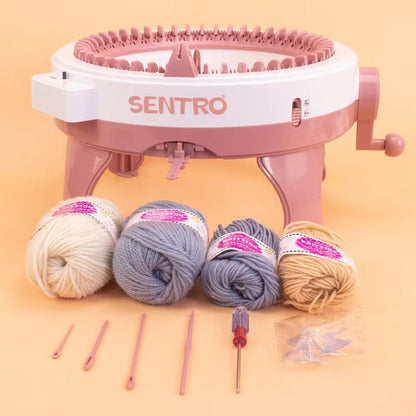 Introducing the 48 Needles Knitting Machine Kit with Row Counter (Bundle48), a pink and white circular knitting machine that includes four balls of yarn in cream, blue, gray, and beige. This comprehensive kit comes equipped with knitting hooks and a screwdriver to meet all your hand knitting needs.