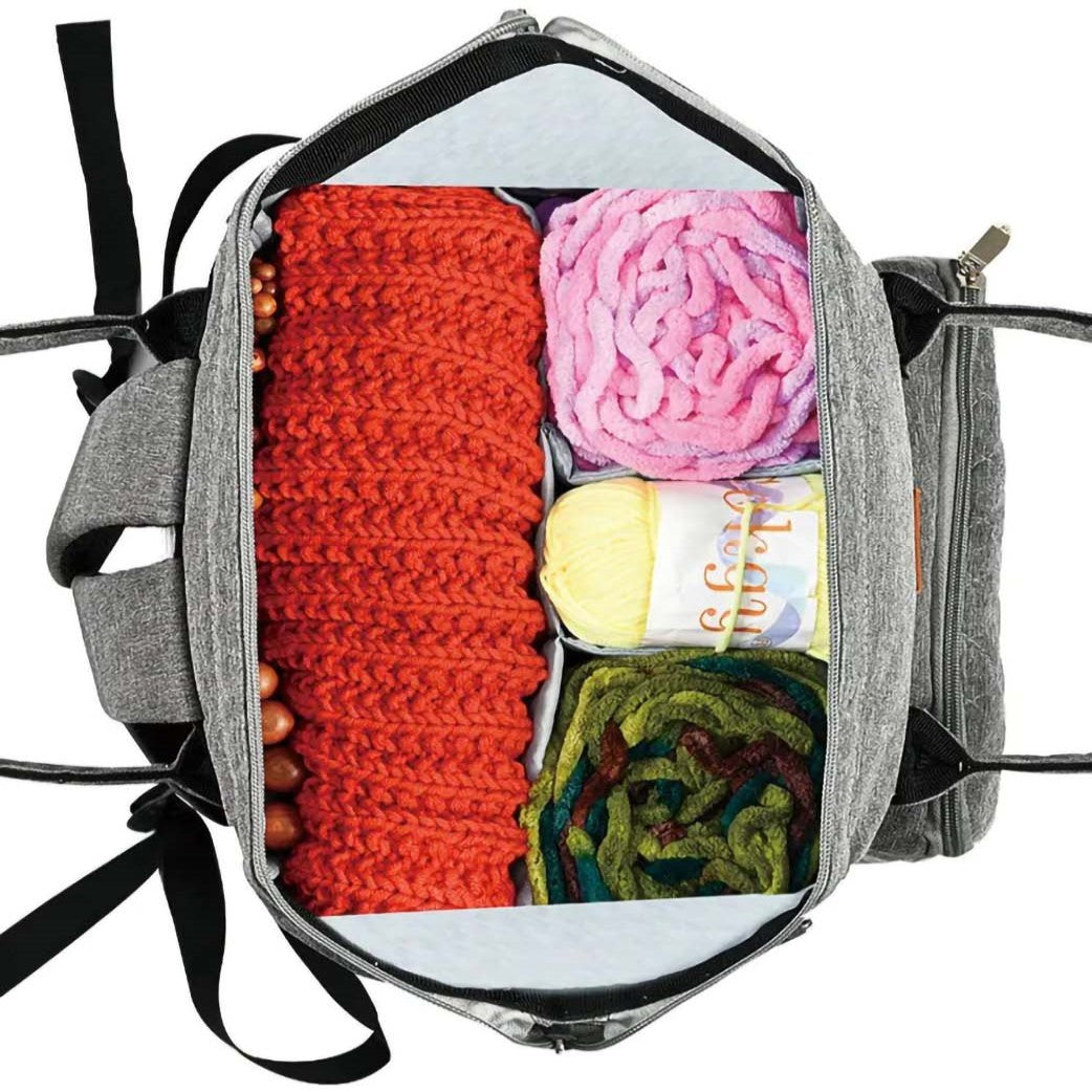 The Oxford Serenity Luxe Bag (bundle) is an open gray bag crafted from durable 600D Oxford fabric, containing red, pink, yellow, and green balls of yarn along with essential knitting and crocheting tools.