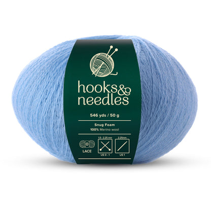 The Snug Foam Yarn 50g, featuring a "hooks & needles" label, is perfect for knitting and crochet projects. Offering 546 yards of light blue, 100% Merino wool at lace weight and weighing just 50 grams, it's ideal for needle sizes US 0-1.