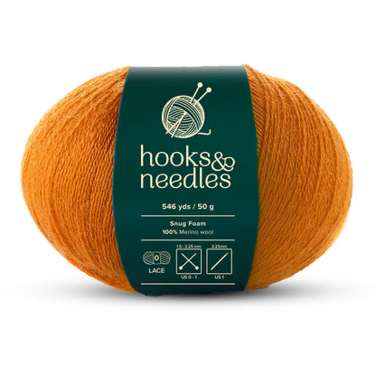 Explore our Snug Foam Yarn 50g, an exquisite lace-weight yarn in a vibrant orange shade. This lightweight ball offers 546 yards of 100% Merino wool, making it perfect for your knitting and crochet projects. It's labeled "hooks & needles" and is best used with recommended needle sizes of 1.5-2.25 mm (US 000-1).