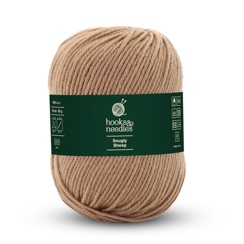 A lightweight ball of tan-colored Snugly Sheep Yarn 50g is labeled with knitting and care symbols on the dark green label, made from 100% wool.