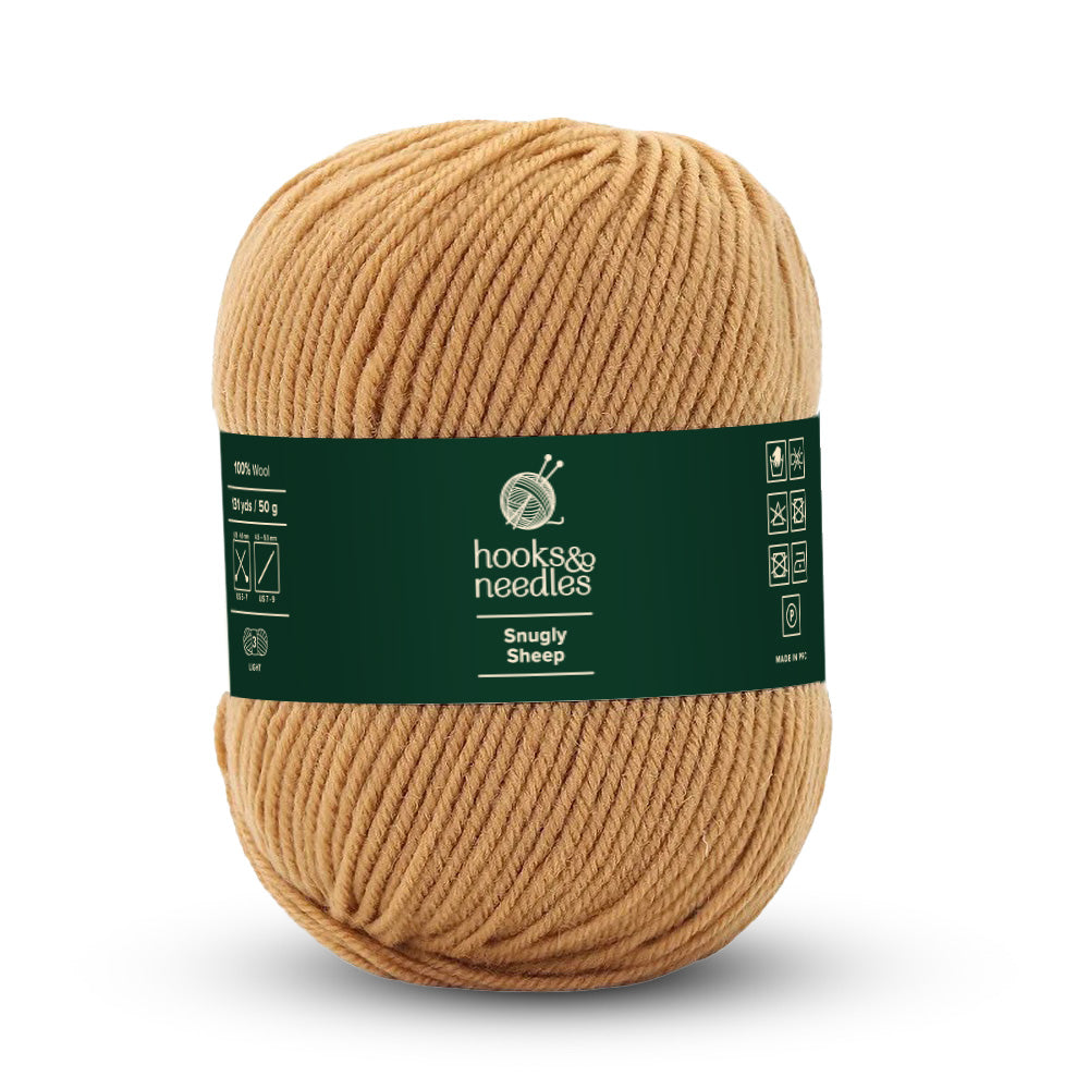 A ball of tan-colored, light-weight yarn labeled "Snugly Sheep Yarn 50g" bears icons on its green label showing it is made of 100% wool and includes care instructions.