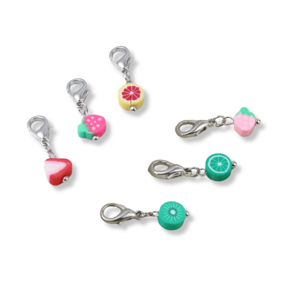 The Enamel Fruit Stitch Marker Set 6Pcs features fruit-themed enamel charms with silver clasps, including a red strawberry slice, pink strawberry, yellow-orange slice, pink berry, green lime slice, and green kiwi slice—perfect as vibrant stitch markers for your knitting and crochet projects.