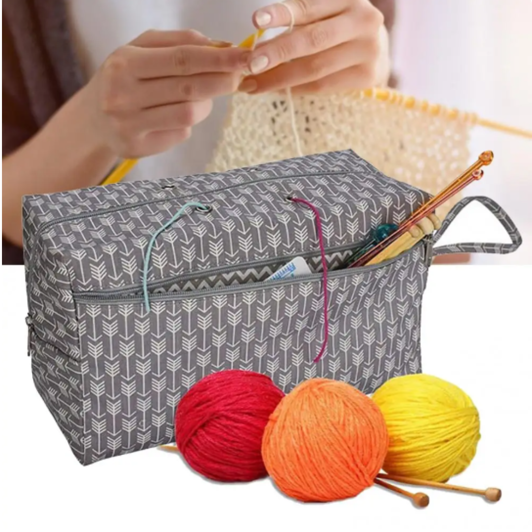 A person is knitting with beige yarn using needles from a Portable Knitting Organizer (Bundle). Nearby, the bundle includes a portable bag that holds three balls of yarn—red, orange, and yellow—providing easy storage and quick access as creativity unfolds.