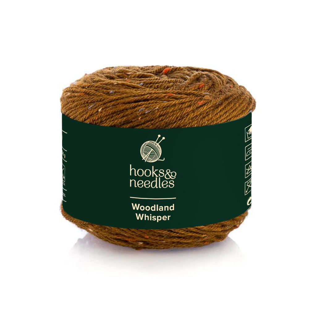 A ball of luxurious Merino wool yarn labeled "Woodland Whisper" with a green band, featuring knitting needles and a ball of yarn logo.