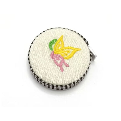 The 150cm Retractable Fabric Measuring Tape, with its round embroidered case showcasing a delightful butterfly design, is ideal for knitting and crocheting measurements.